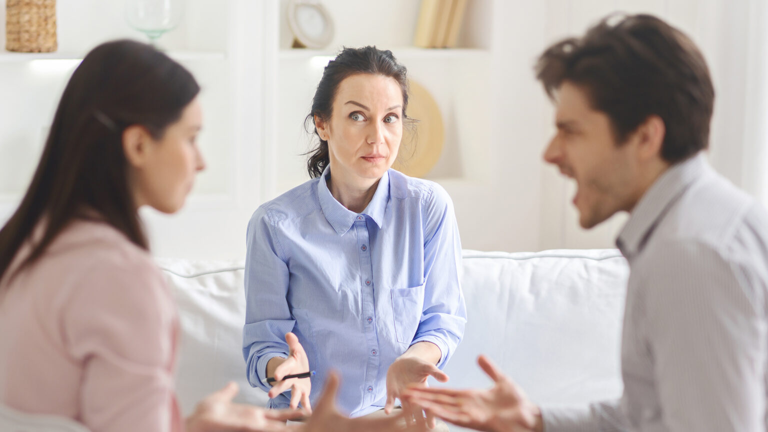 A young couple and a lady counselor engage in a meaningful therapy session, focusing on emotional growth and relationship healing in a welcoming setting.